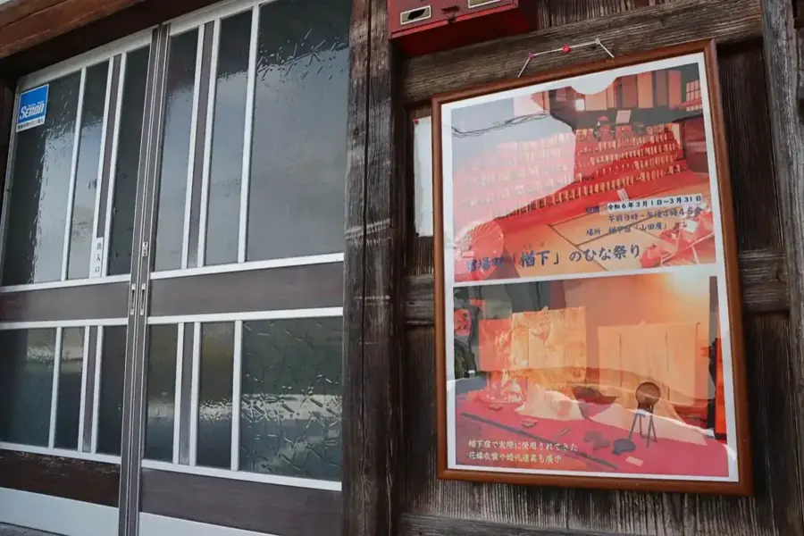 建物入口に置かれた雛祭りの案内板 = 2024年3月9日 楢下