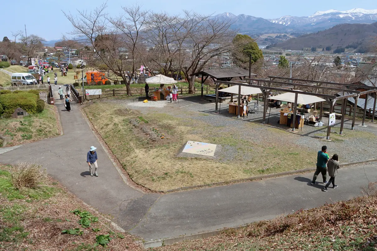 蔵王連峰を背景に写真手前に足湯と奥にキッチンカー = 2024年4月7日 月岡公園