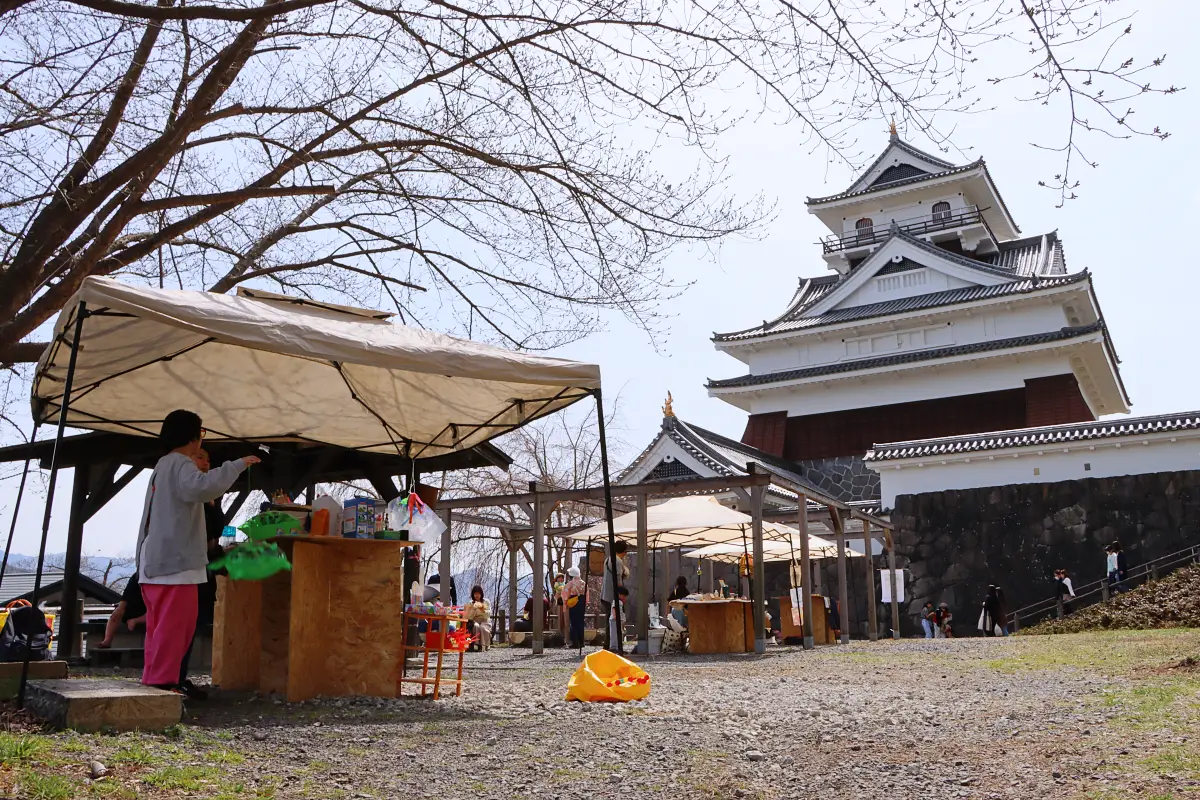 城前の出店者らと中央に飲食スペース = 2024年4月7日 上山城正門前