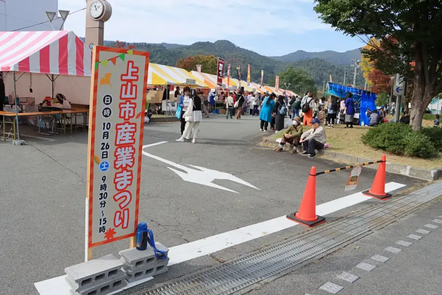 イベントの看板と駐車場に並ぶ出店者 = 2024年10月26日 三友エンジニア体育文化センター正面駐車場