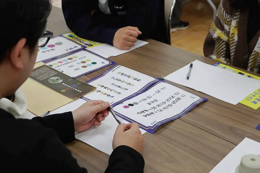 ワイワイ話しながら謎解きする参加者ら(1) = 2025年3月9日 アビヤント・K