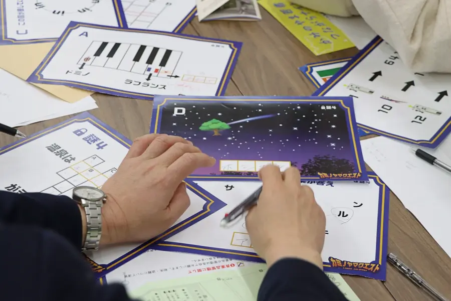 ワイワイ話しながら謎解きする参加者ら(3) = 2025年3月9日 アビヤント・K