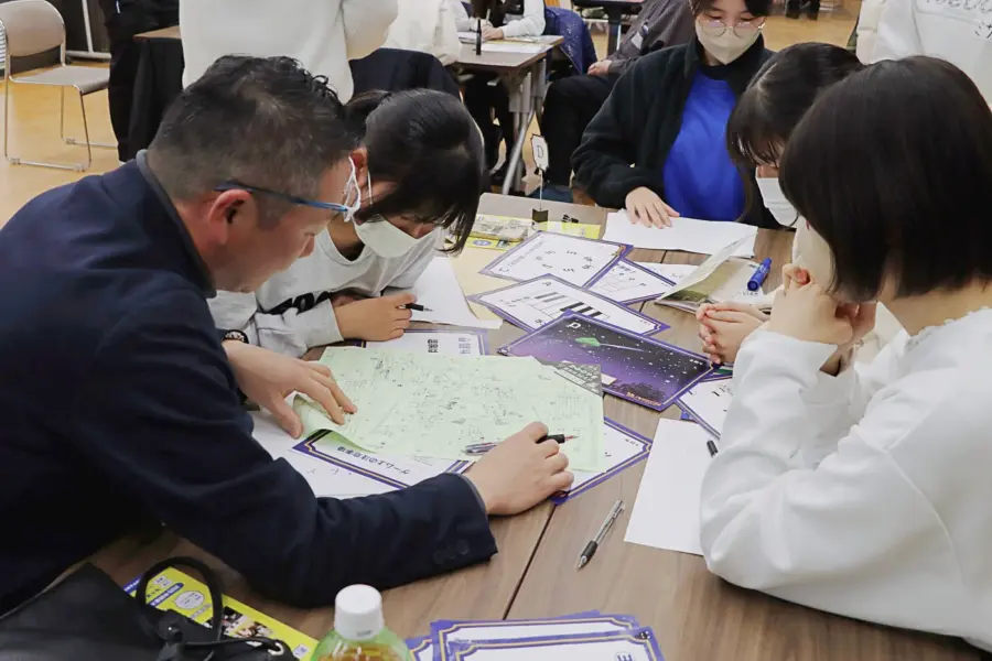 ワイワイ話しながら謎解きする参加者ら(4) = 2025年3月9日 アビヤント・K