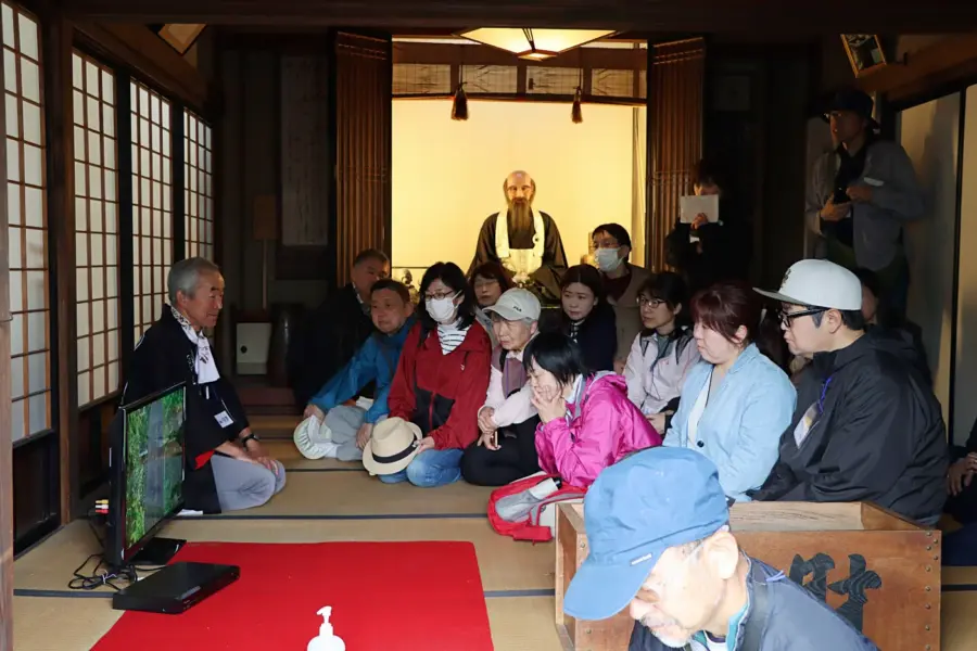 春雨庵の中でビデオを見る参加者ら = 2025年5月31日 松山
